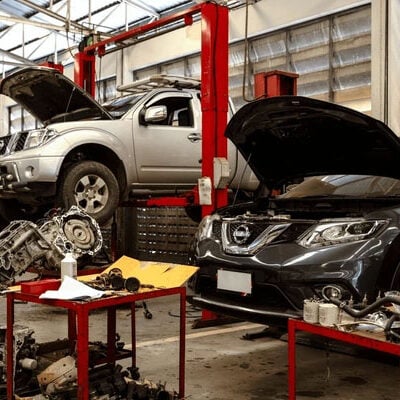 Vehicles on lifts with tools and parts nearby. Car maintenance in progress.
